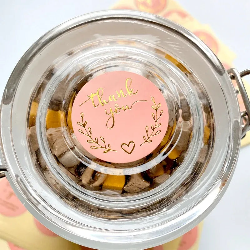 Pink round thank you sticker with gold script on jar contents