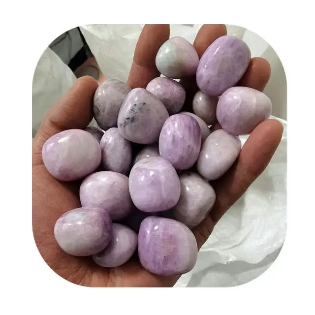 Purple kunzite tumbled stones, mixed light and medium lavender pieces in hand