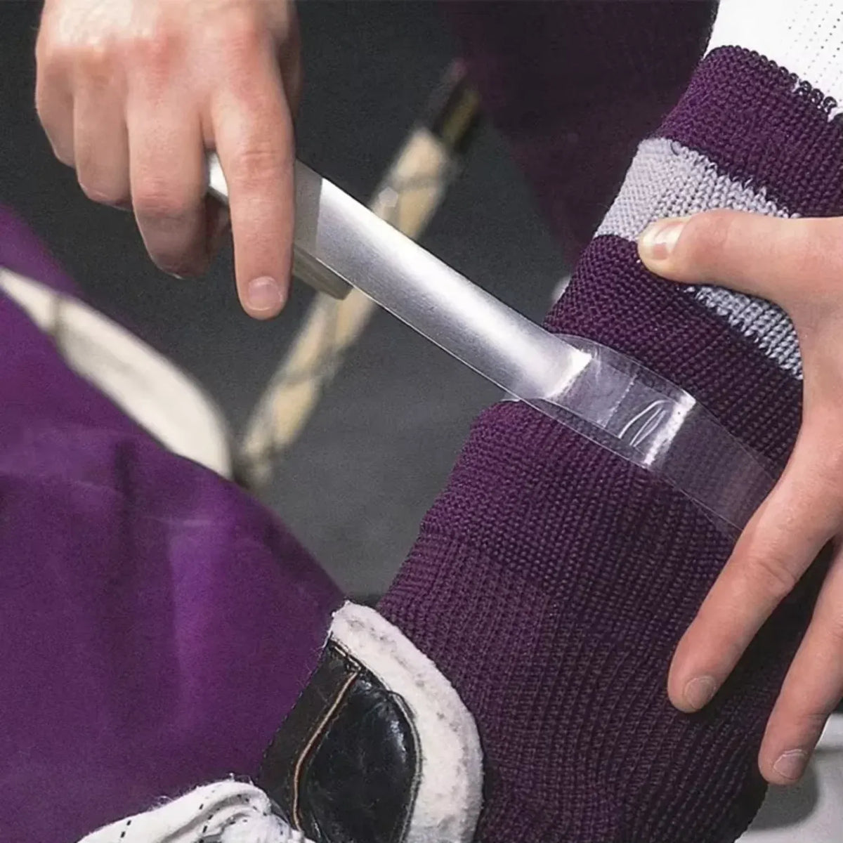 Purple elastic shin grip tape applied to a sock on a foot