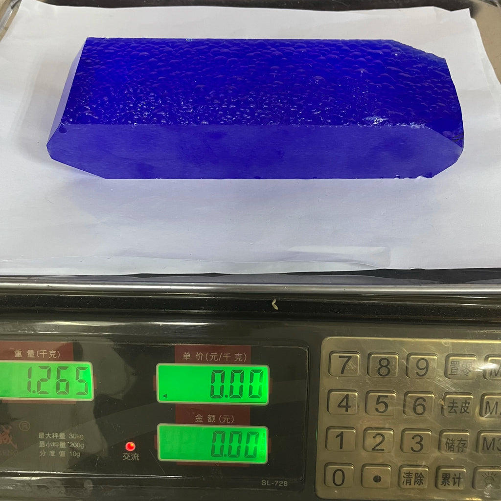 Blue synthetic hydrothermal crystal prism on tray, shown beside digital scale readouts.