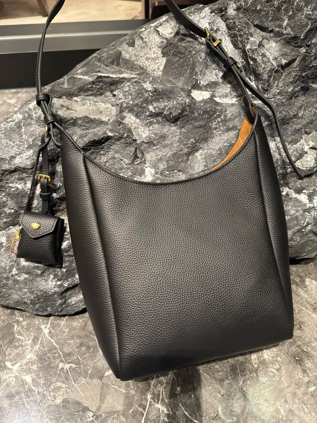 Black genuine leather hobo shoulder bag with pebble texture, adjustable strap, and small detachable pouch accessory.