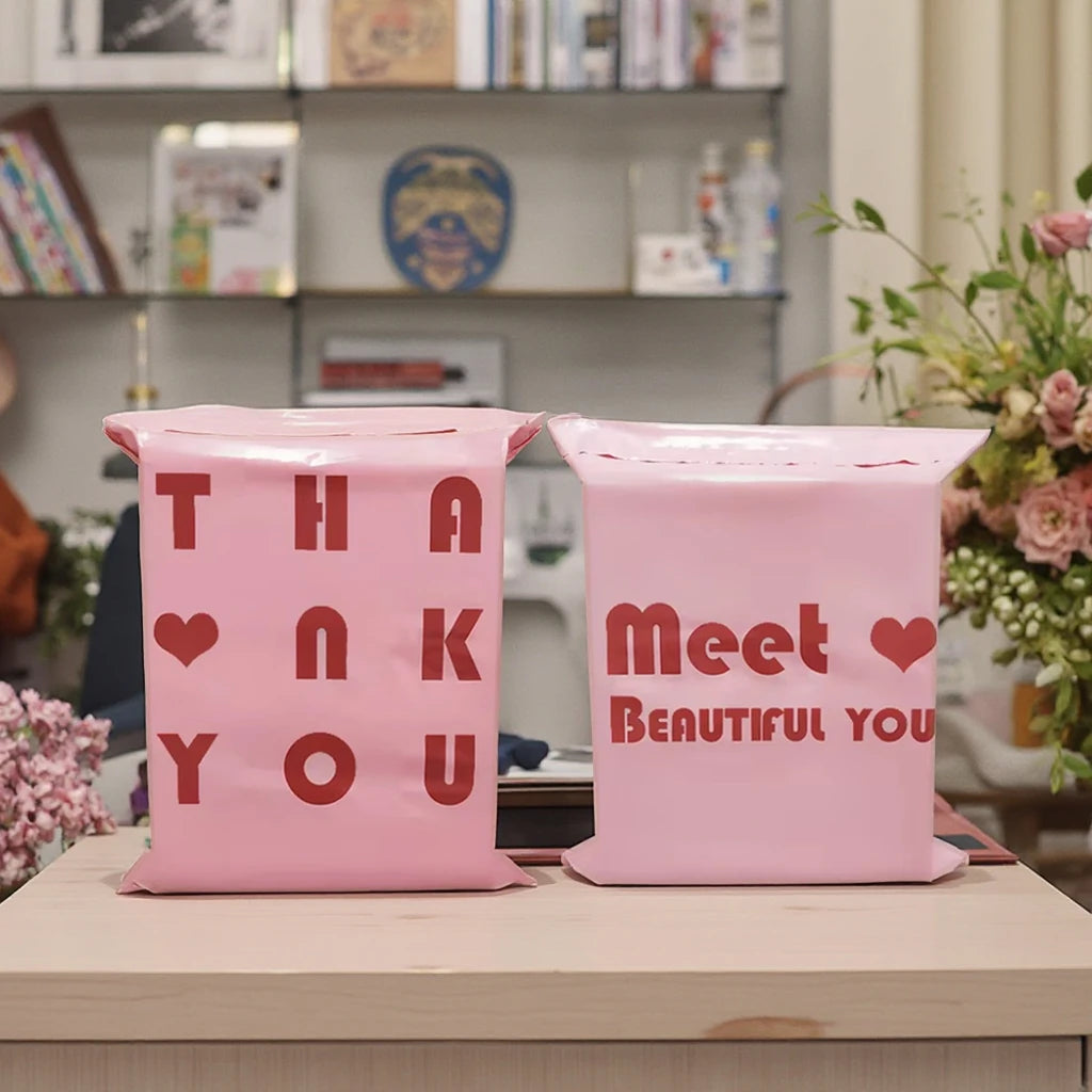 Pink Iove items printed shipping bags on a tabletop