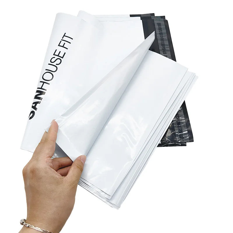 White poly mailer bags held by hand, glossy plastic with SANHOUSE FIT branding