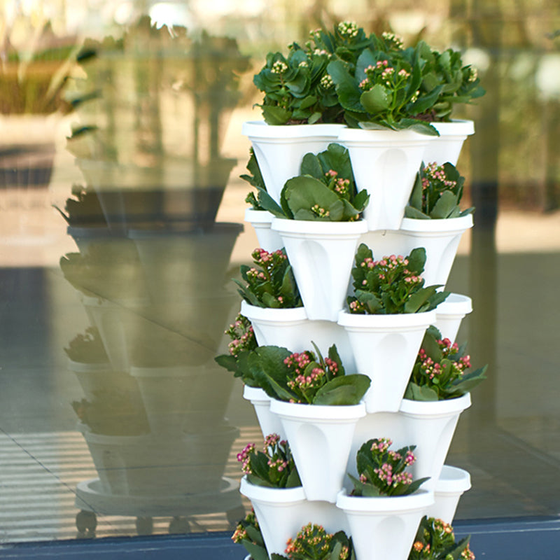 Stackable vertical plastic flower planter tower with white pots and blooming green foliage