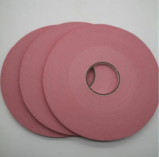 Double-sided heat resistant foam adhesive tape rolls, red stacked on a white surface