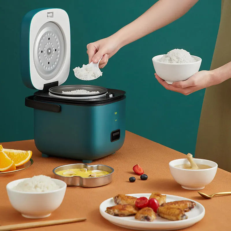 Teal mini electric rice cooker on countertop with rice and serving bowls