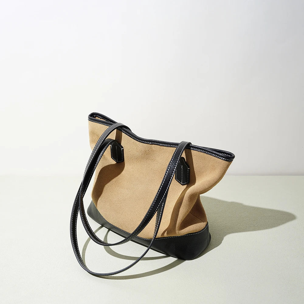 Vintage beige suede underarm tote bag with black leather trim, contrast stitching, and minimalist structured design.