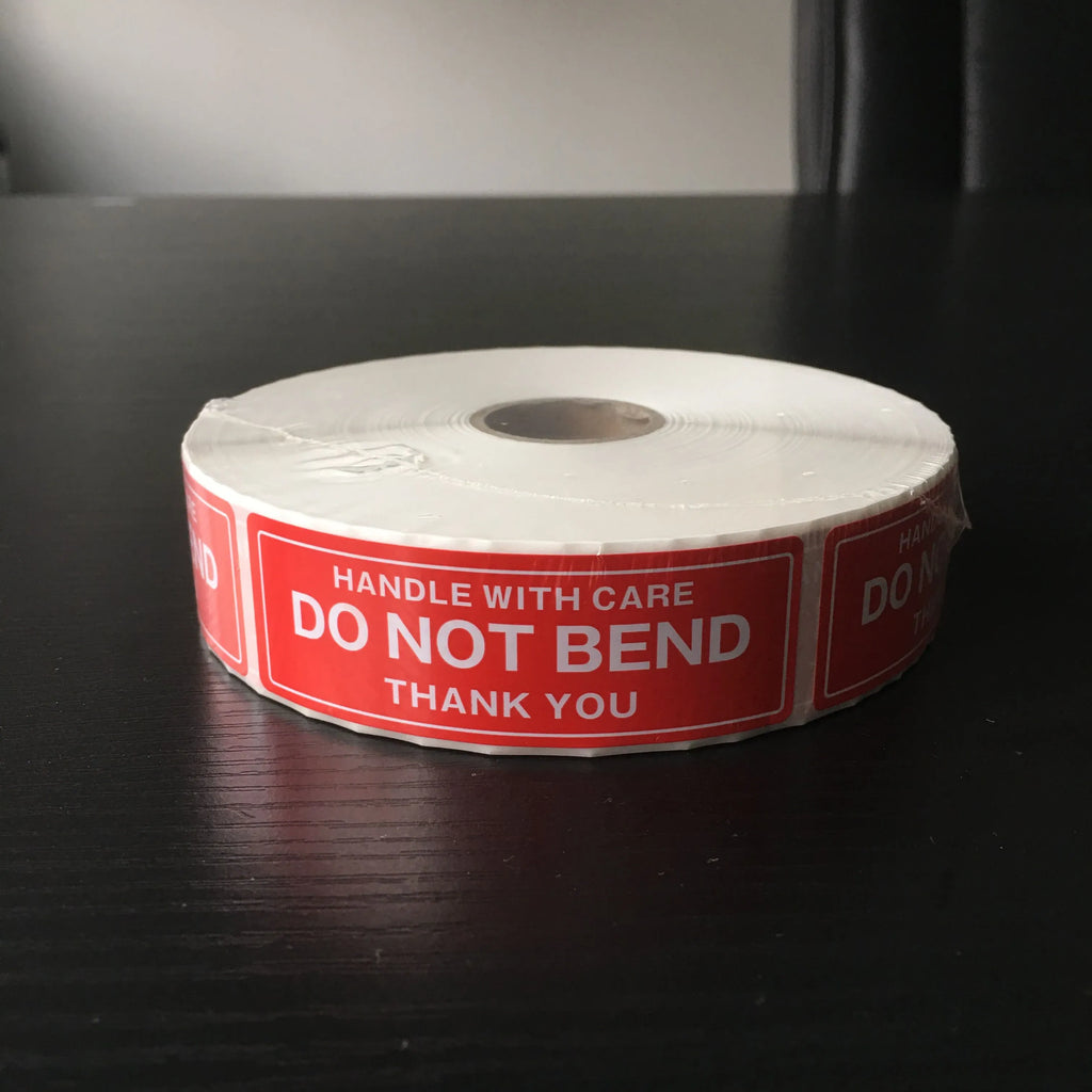 Coiled roll of red “Do not bend” warning stickers with “Handle with care” text