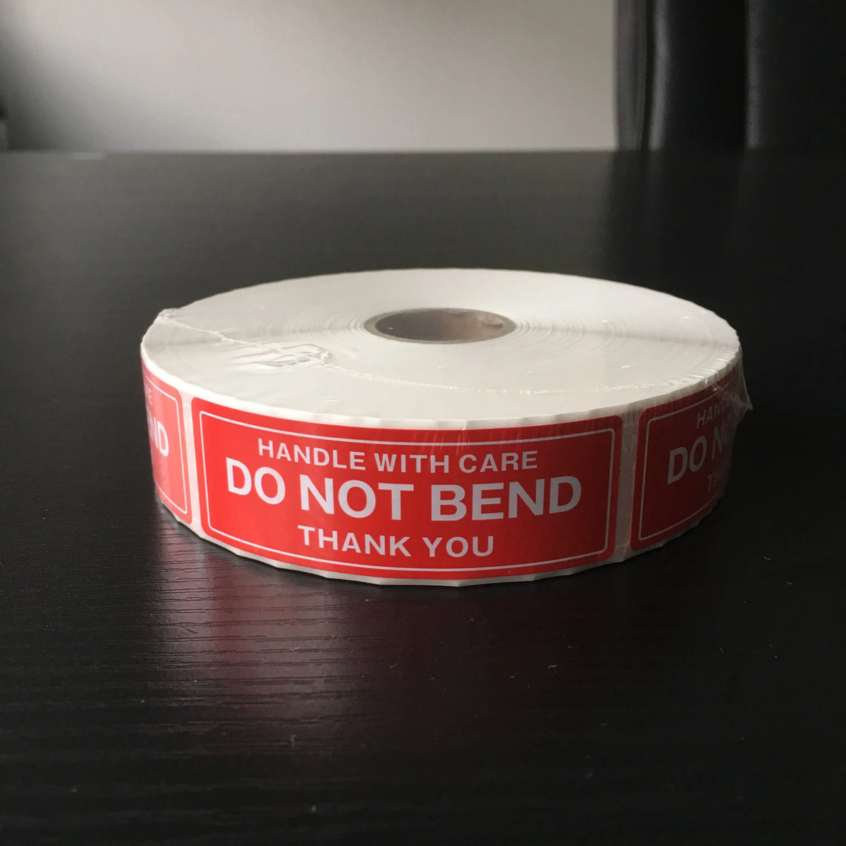 Coiled roll of red “Do not bend” warning stickers with “Handle with care” text