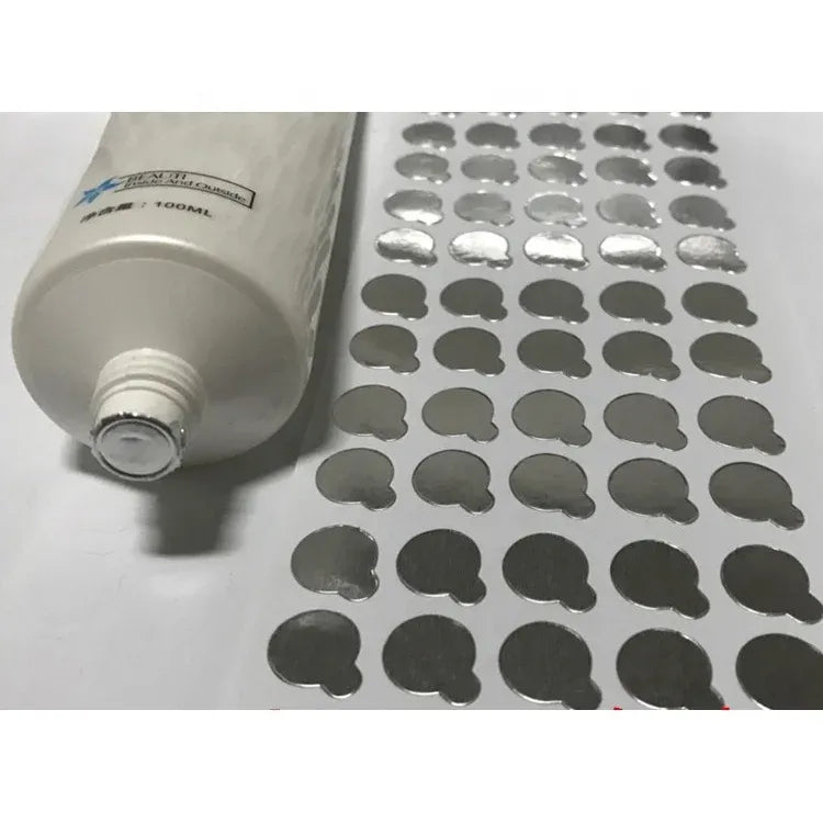 Round aluminum seal stickers spread out beside a bottle seal applicator, silver
