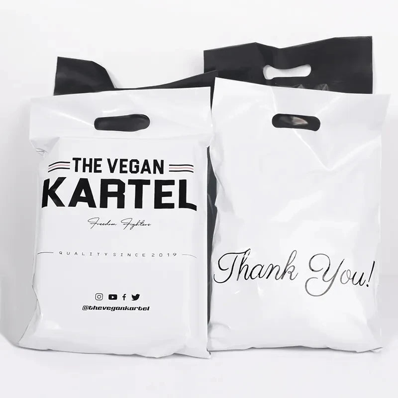 Two white poly mailer bags with handles: “THE VEGAN KARTEL” and “Thank You!” prints.