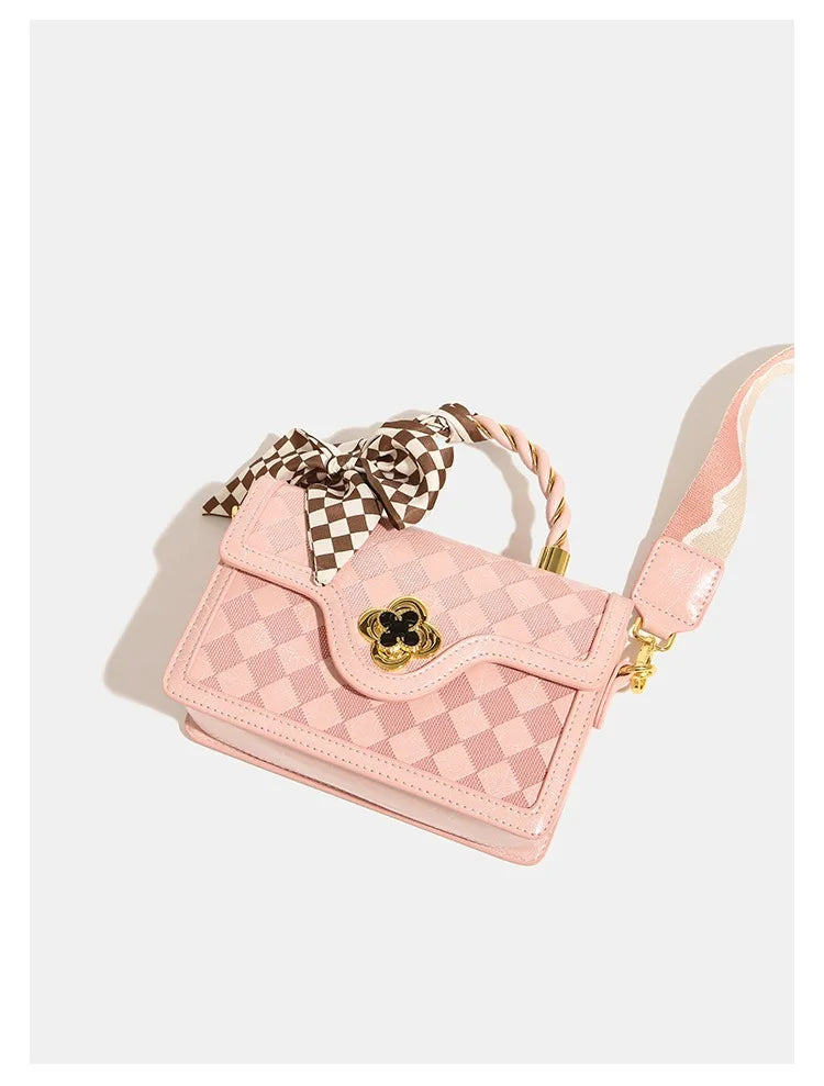 Pink plaid leather trunk handbag with gold flower clasp, twisted handle, scarf accent, and crossbody shoulder strap.