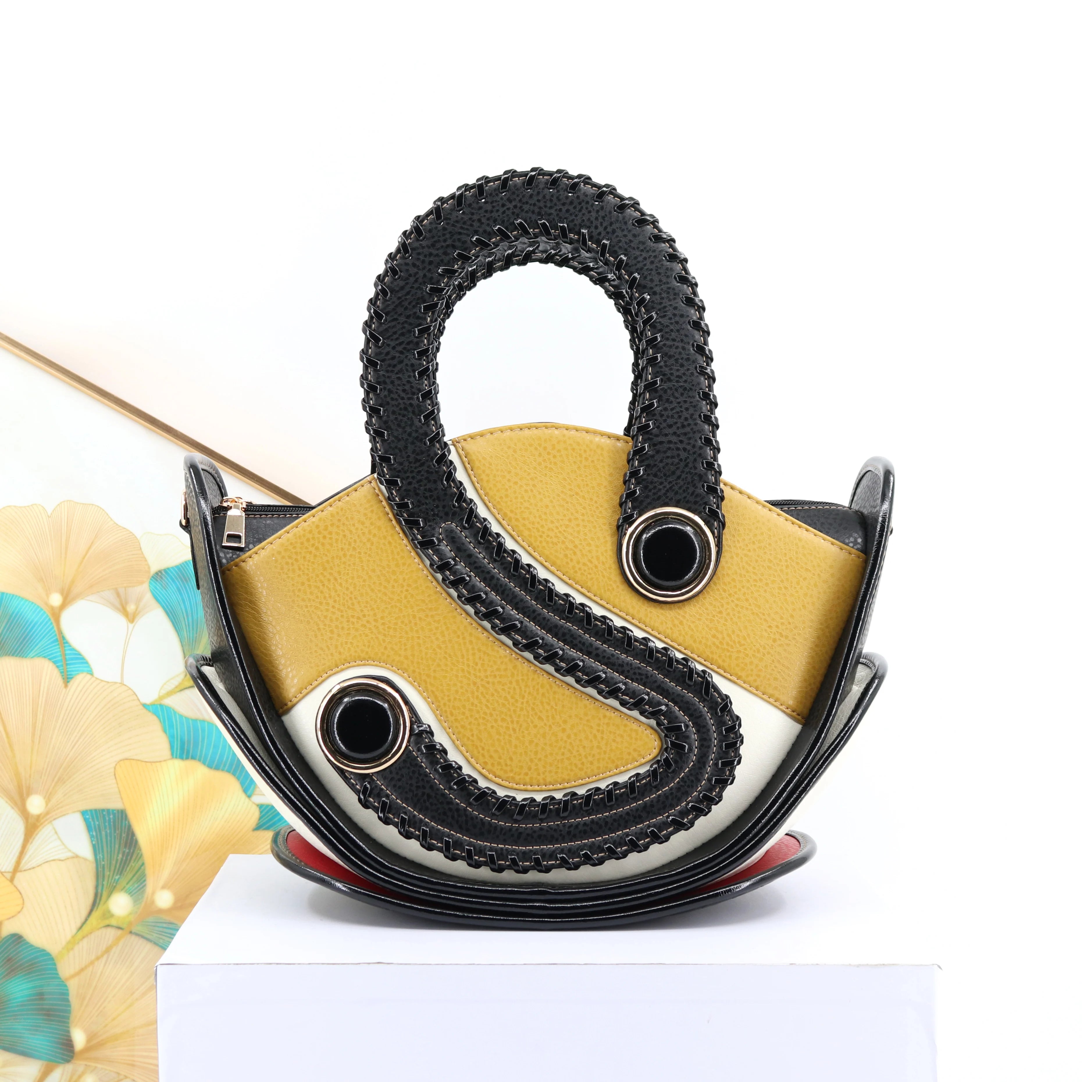 Unique designer handbag in yellow, white, and black leather with structured whipstitch trim and circular hardware.