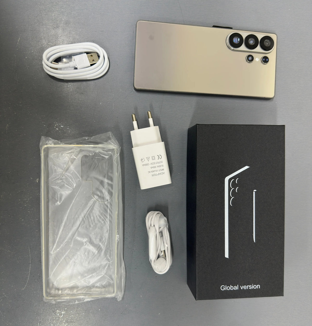 Gold smartphone with quad cameras and included charger, cable, and protective case