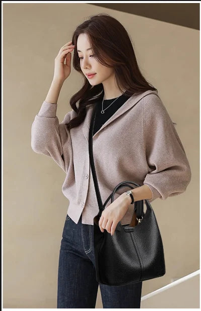 Black pebbled leather bucket handbag, versatile commuter crossbody style with top handles and adjustable shoulder strap.