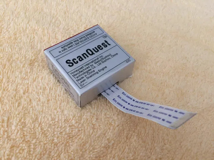 ScanQuest scanner module with barcode label and ribbon cable on tabletop