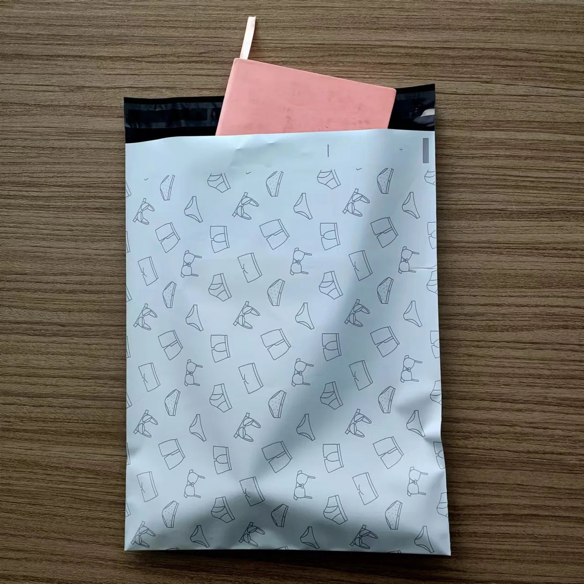 White plastic mailer with light-blue repeating icon pattern and sealed top edge.