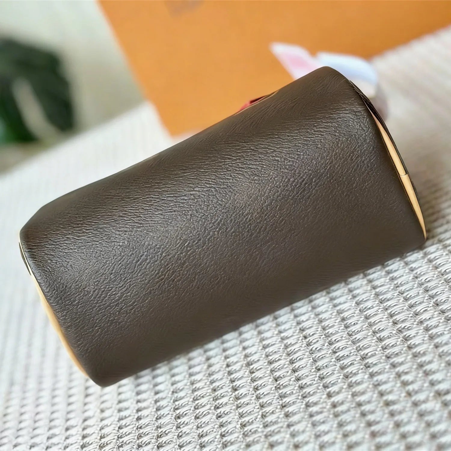 Cylindrical brown leather luxury designer trunk handbag with grained texture and sleek minimalist style.