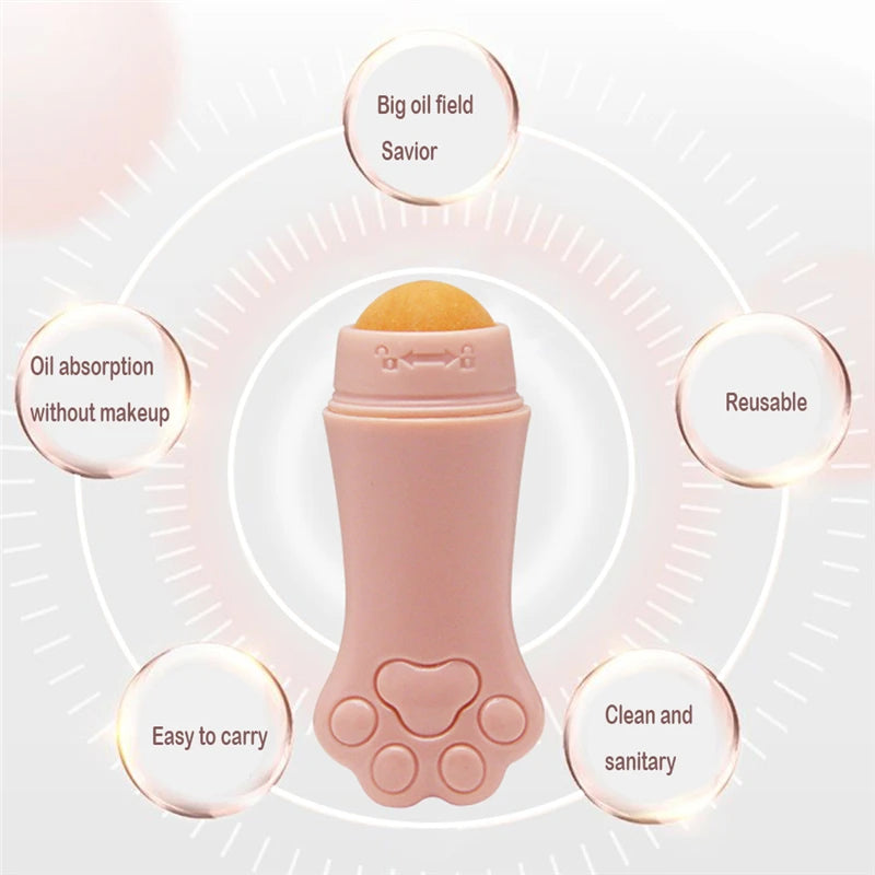 A pink, cat-paw-shaped facial oil-absorbing roller with a yellow volcanic stone ball, surrounded by benefit bubbles.