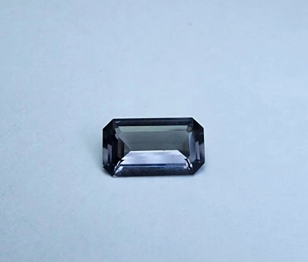 Gray emerald-cut spinel gemstone with beveled corners, step-facets