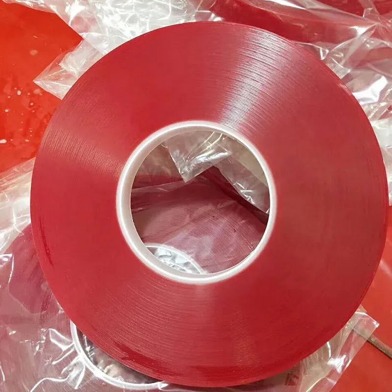 Red double-sided polyester tape roll with clear inner core, glossy adhesive backing
