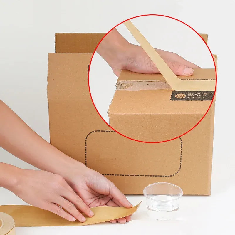 Hand applying kraft paper packing tape to a cardboard box after wetting with water