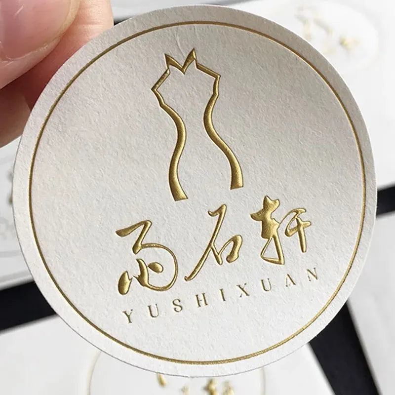 White round sticker label with gold cat and Chinese text logo, embossed.