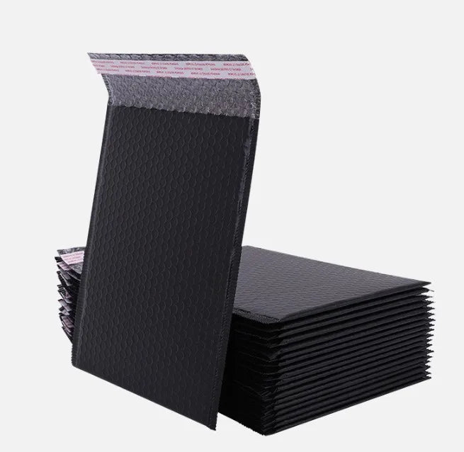 Black plastic bubble mailer envelopes stacked, textured bubble surface and printed strip