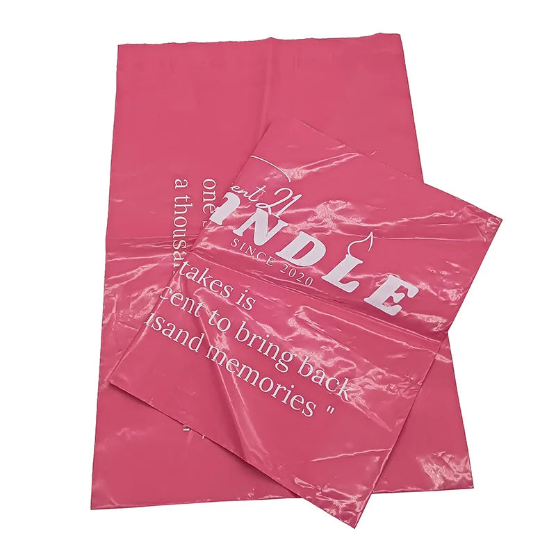 Pink poly mailer bags with white logo print and quote text, two bags layered