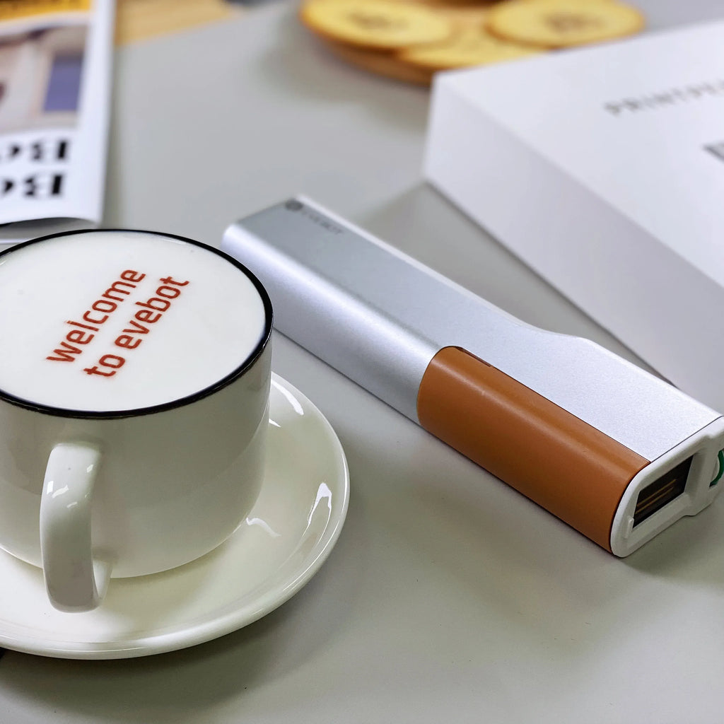 Handheld edible ink printer with brown cartridge, silver body and side window