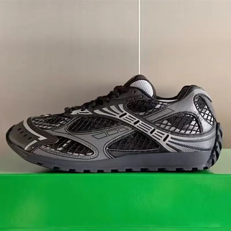Luxury designer men's sneakers in black and grey, featuring genuine leather, mesh panels, and a chunky rubber sole.