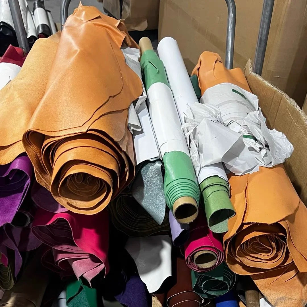 Rolls of premium leather in tan, green, pink, and white for manufacturing luxury handbags and designer trunks.