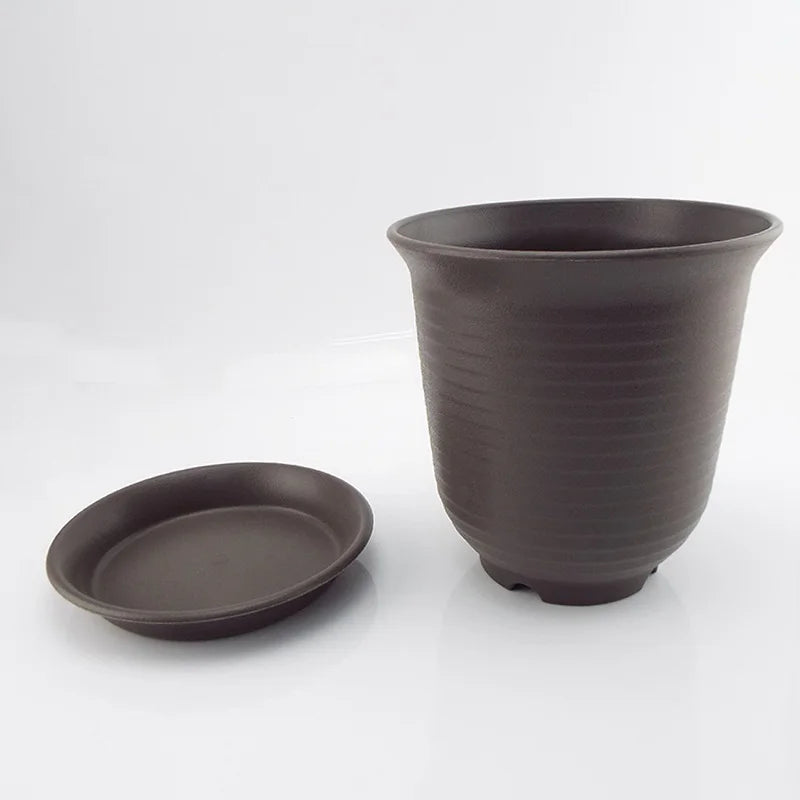 Dark gray plastic nursery pot with matching saucer tray next to it.