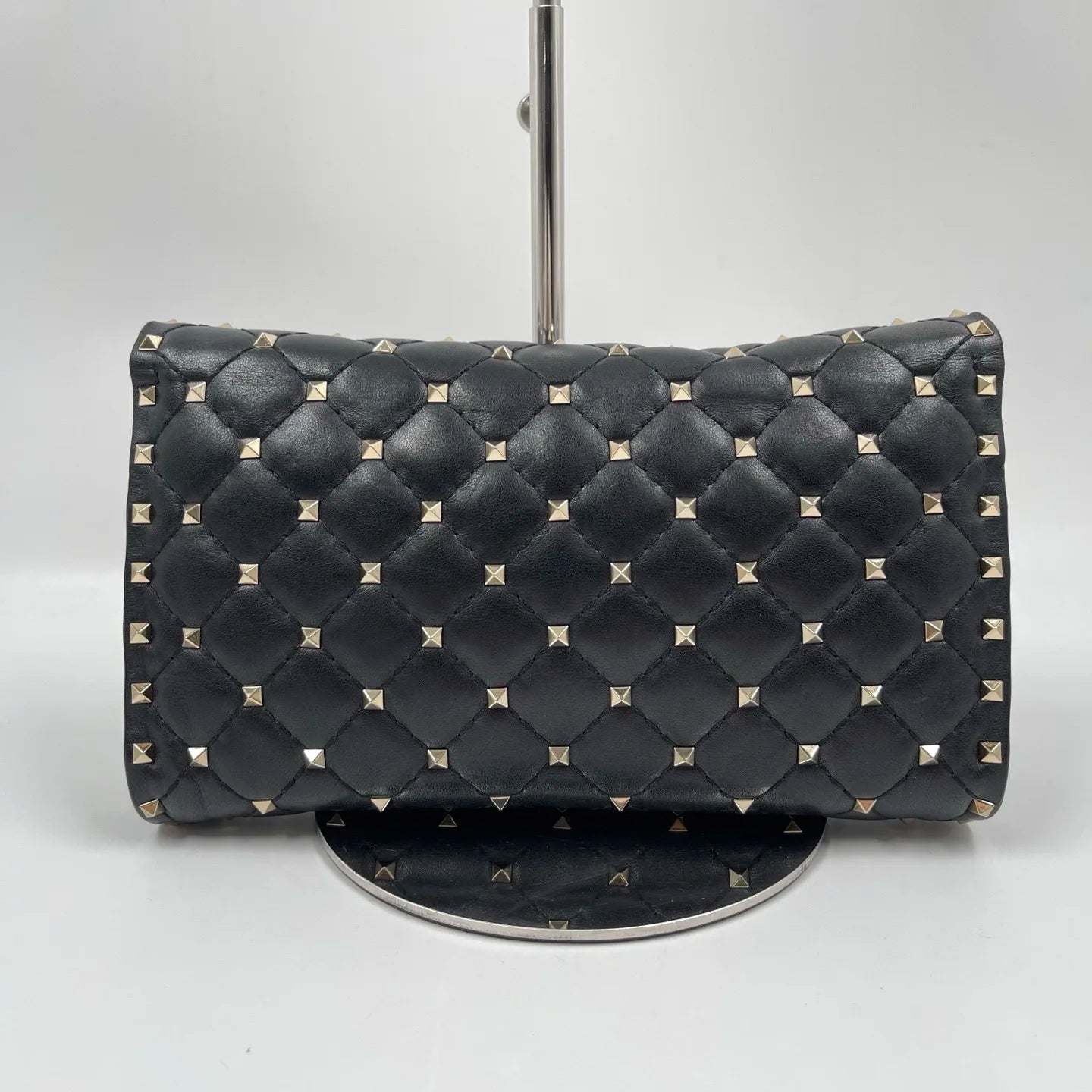 Pre-owned black quilted leather designer handbag with gold pyramid stud rivets, styled as a luxury shoulder bag.
