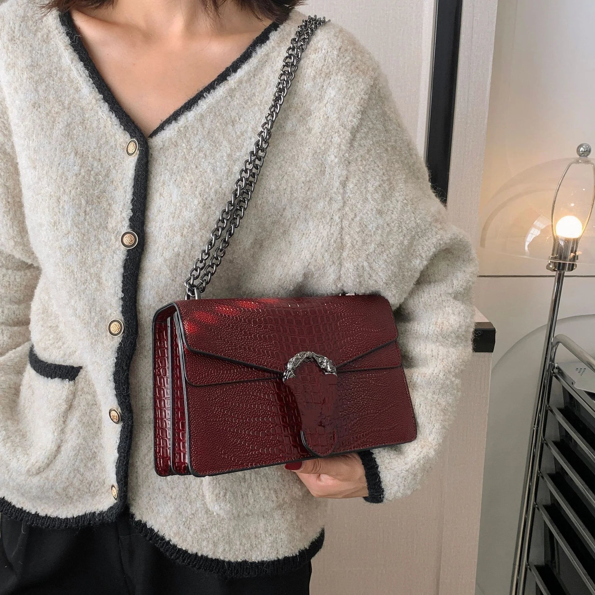 Luxury burgundy crocodile-pattern crossbody trunk bag with silver chain strap and metal clasp.