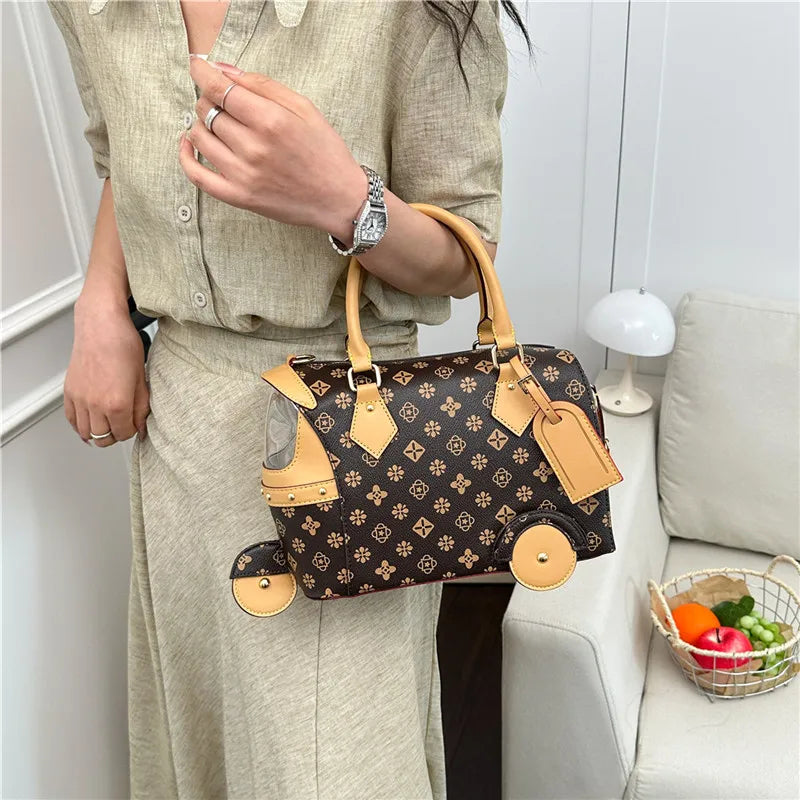 Brown PU leather trunk handbag with floral print, tan trim, and unique tricycle wheel accents for women.