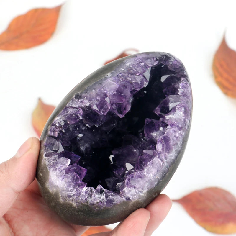 Amethyst crystal geode egg with purple druzy interior, held in a hand