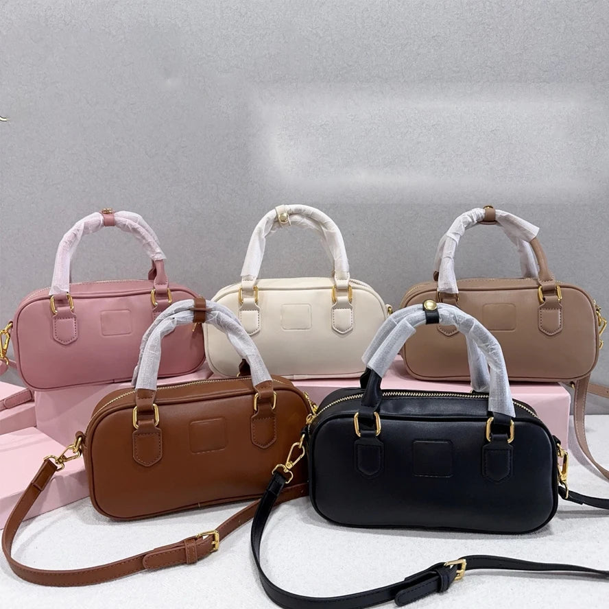 Set of five luxury leather trunks in pink, white, beige, brown, and black with gold hardware and shoulder straps.