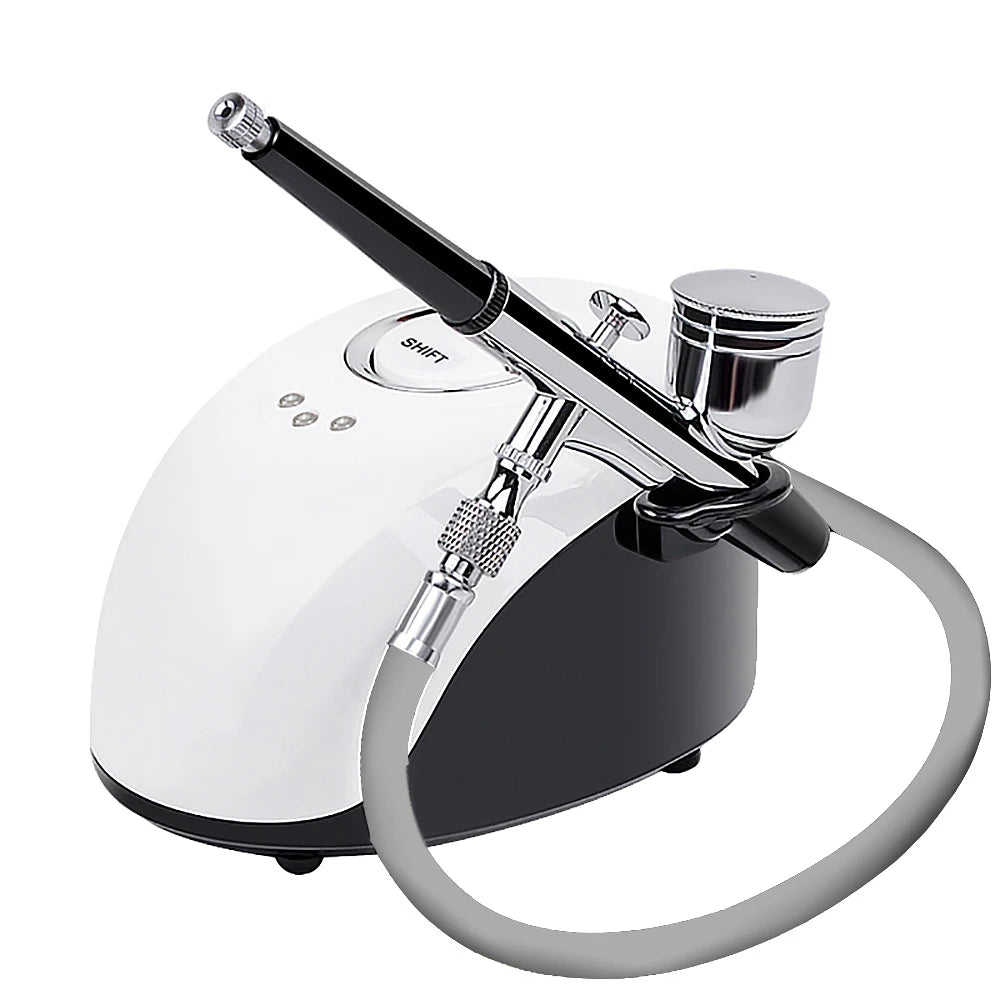 White and black facial airbrush compressor machine with a chrome spray gun and a grey connecting hose.