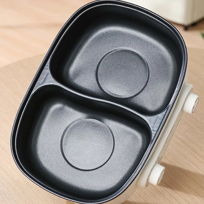 Black non-stick dual insert pan with two heating circles, fitted in the electric pot