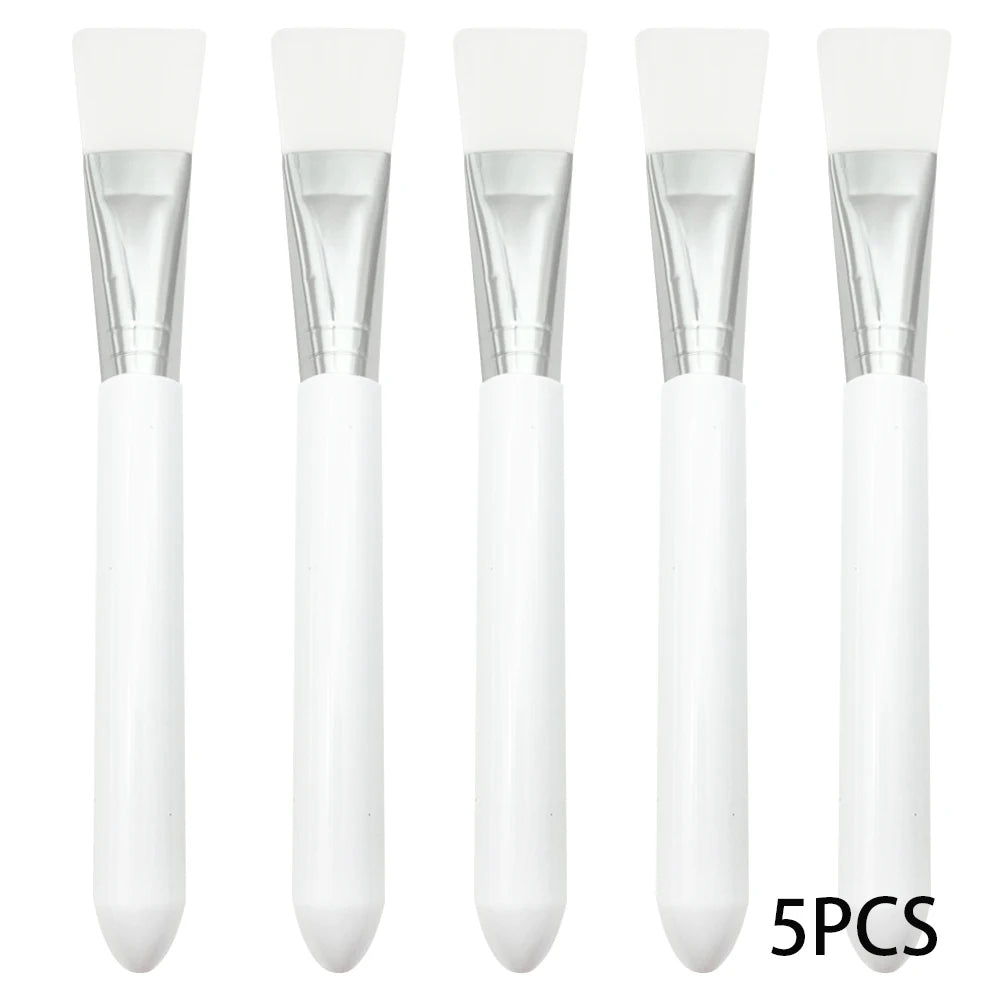 Five white silicone facial mask brushes with silver ferrules and smooth white handles arranged in a row.