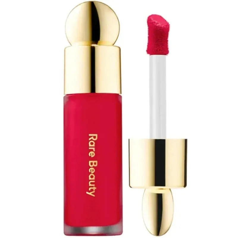Rare Beauty waterproof liquid blush and lipstick in vibrant red with a gold cap and precision applicator wand.