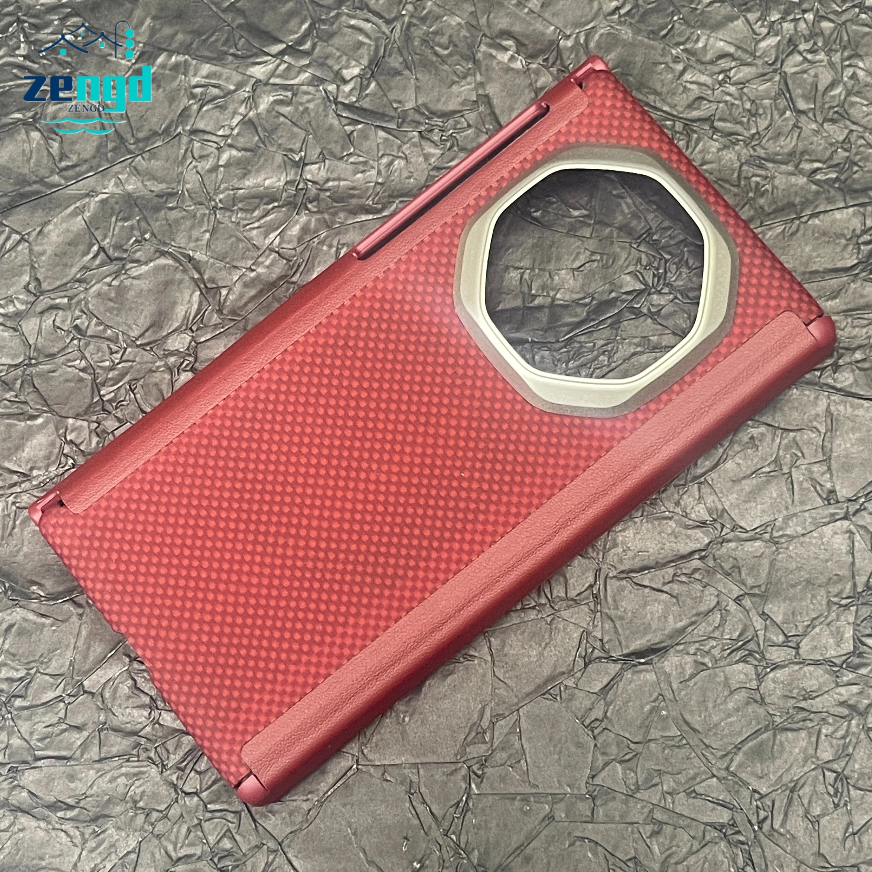 Red carbon fiber-textured folding phone case with a large, octagonal camera cutout, resting on a black crinkled surface.