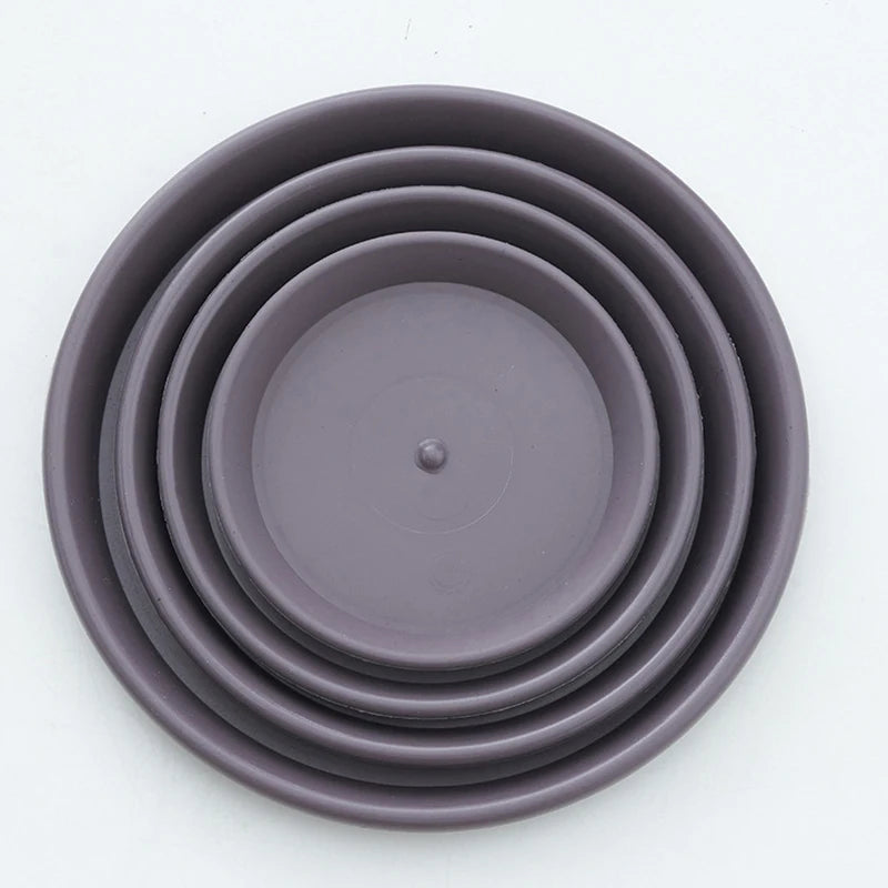 Stacked dark gray nested plastic plant pots, with circular drainage hole details.