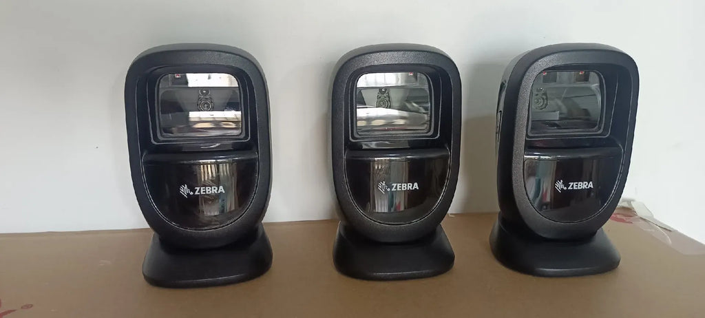 Three Zebra DS9308 desktop barcode scanners in black charging cradles