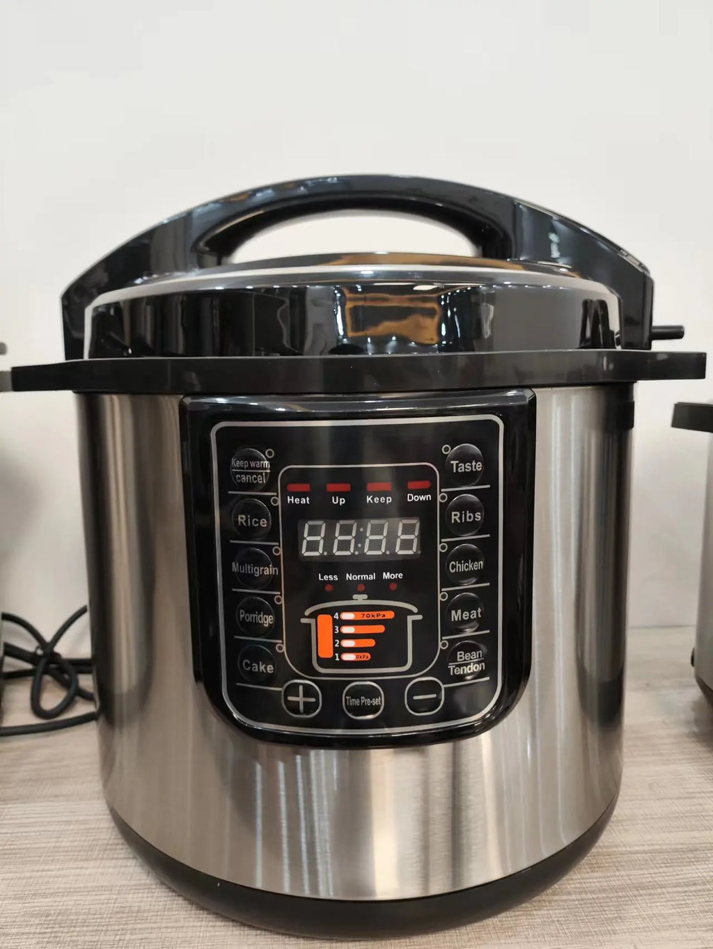 Stainless electric pressure cooker with black control panel and timer-style screen