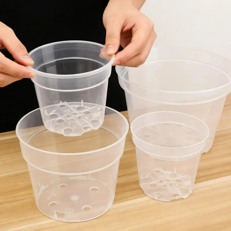 Clear plastic nursery pots held open/stacked, transparent sides and drainage holes on base