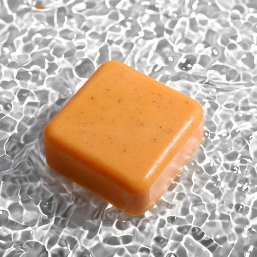 Orange turmeric supplement cube for anti-inflammatory support resting on textured glass surface.