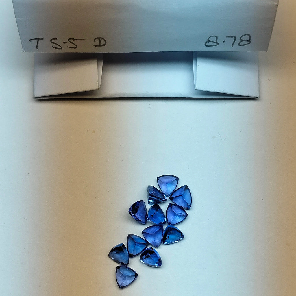 Loose blue trillion-cut gemstones near an open storage box