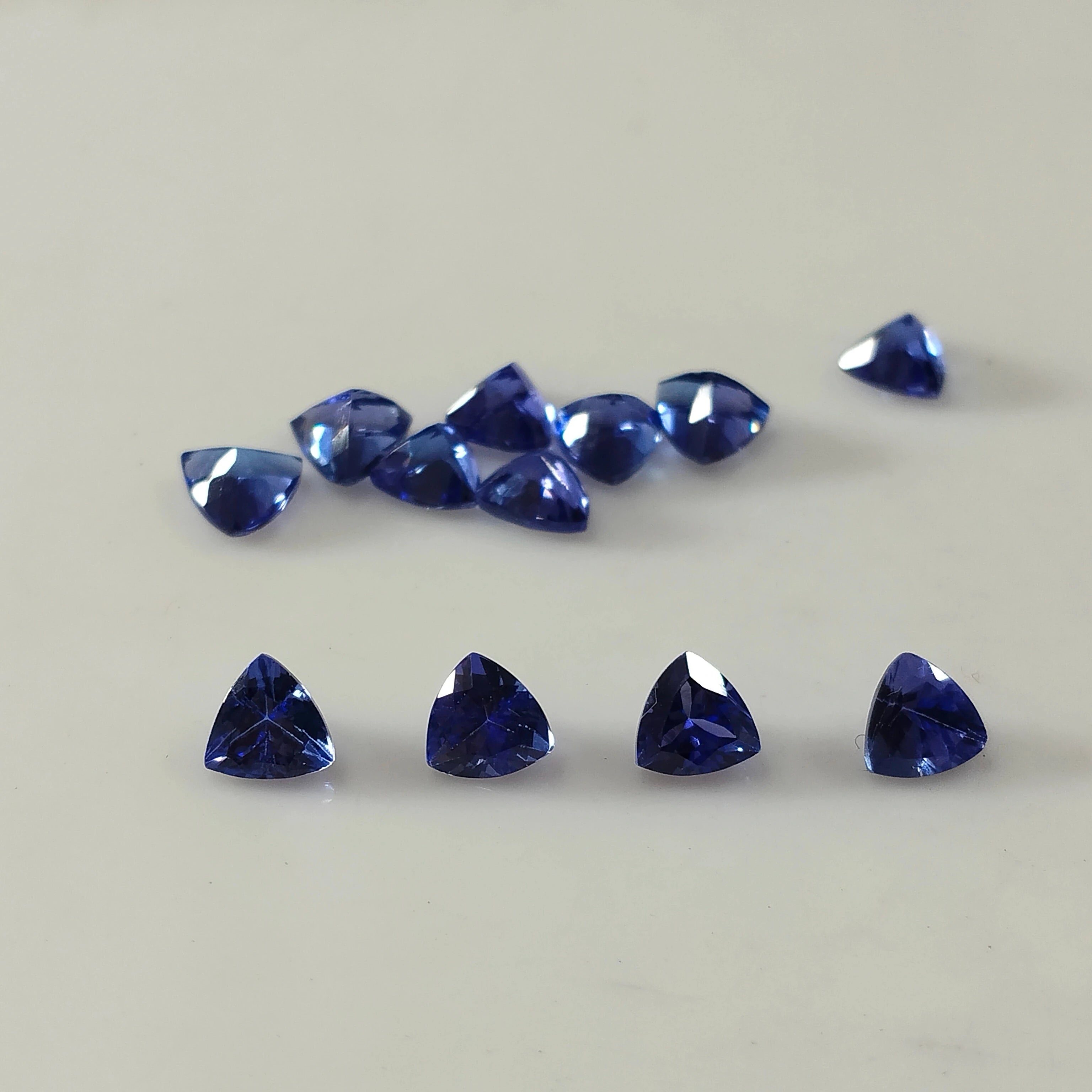 Loose blue trillion-cut gemstones arranged in a row with one single stone
